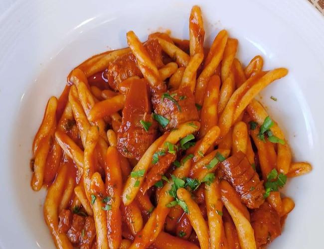 Pasta con sugo di pomodoro e carne, decorata con prezzemolo.